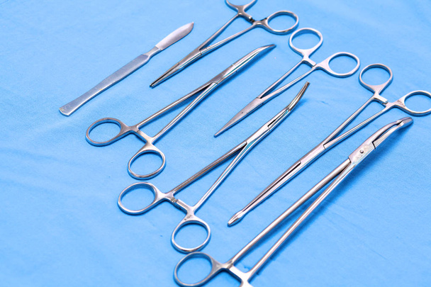 Instrumentos e ferramentas cirúrgicos, incluindo bisturis, pinças e pinças dispostos em uma mesa para uma cirurgia - Foto, Imagem