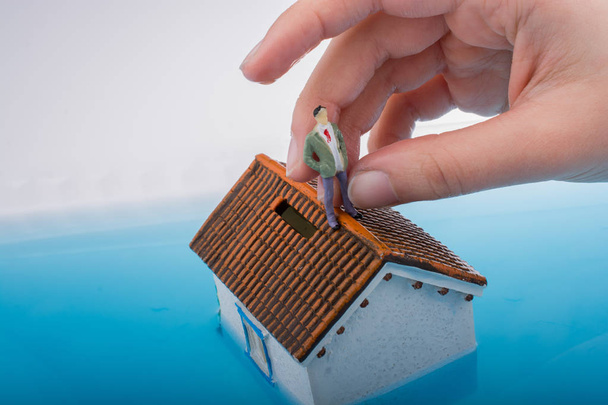 Model house and a man figurines in water - Foto, imagen