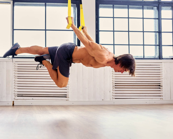 Ο άνθρωπος, η άσκηση με ιμάντες trx γυμναστήριο - Φωτογραφία, εικόνα