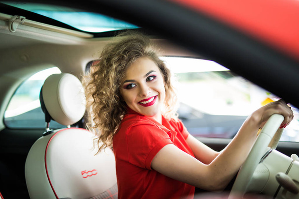 Rijden rond de stad. Jonge aantrekkelijke vrouw lachend en rechte kijken tijdens het rijden van een auto - Foto, afbeelding