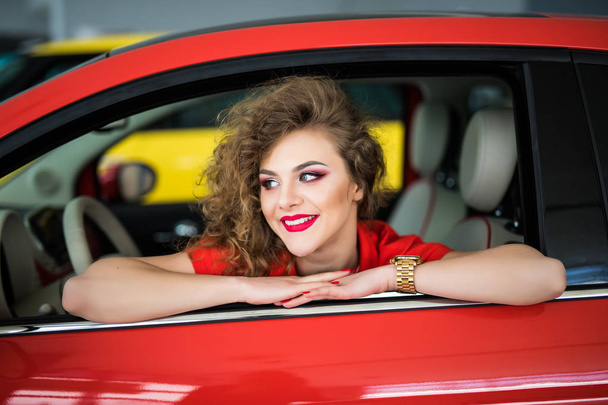 Mujer joven en su nuevo coche sonriendo desde las puertas del coche
 - Foto, Imagen