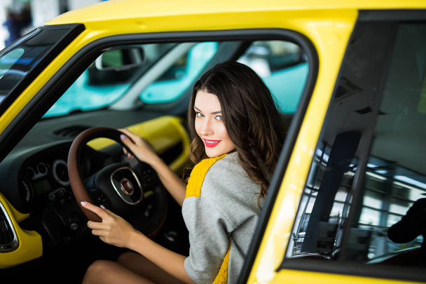 Beautiful Smiling woman driving yellow car, attractive girl sitting in automobile, portrait. - Photo, Image