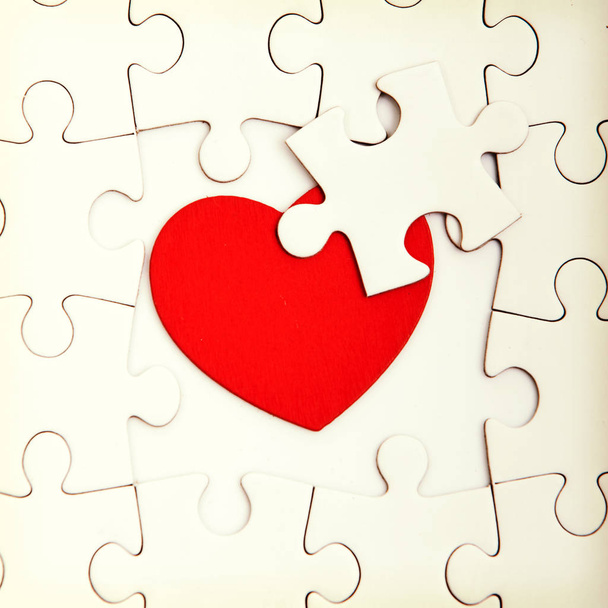 Jigsaw puzzle with blank white pieces and red heart. - Foto, afbeelding