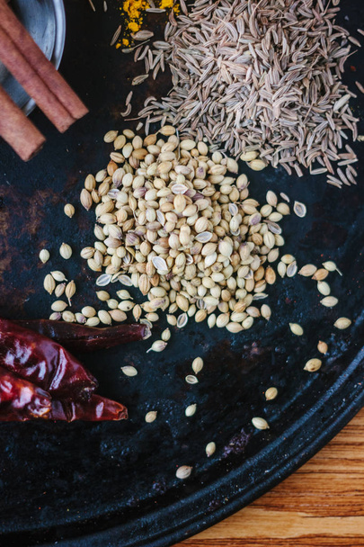 Coriander seeds on black metal plate surrounded by spices. - Photo, Image