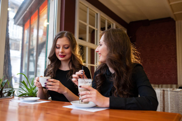Дві красиві дівчата п'ють каву
 - Фото, зображення