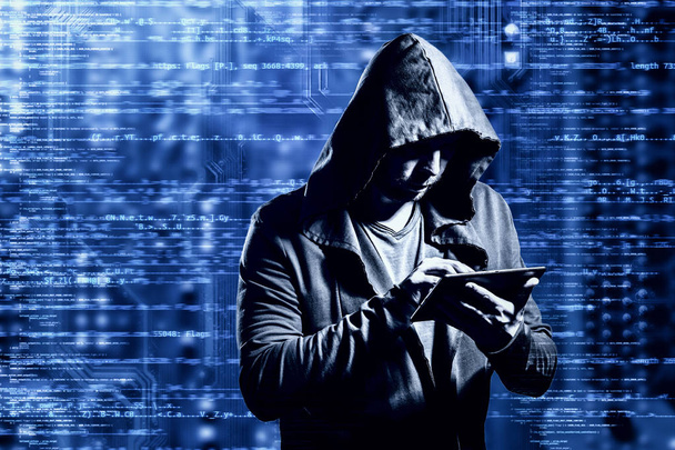 Internet crime concept. Dangerous hacker, in hoodie shirt and dark digital background around, stealing your data. - Photo, Image