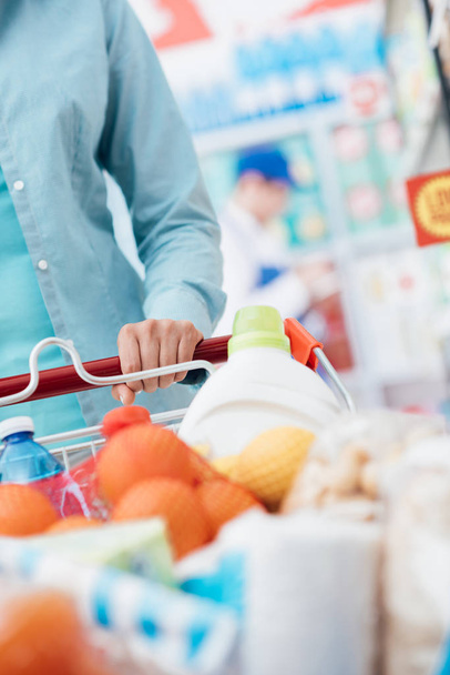 Woman pushing shopping cart at supermarket - Foto, imagen