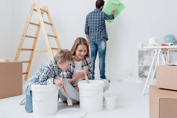 mother and son stirring paint in bucket  - Φωτογραφία, εικόνα