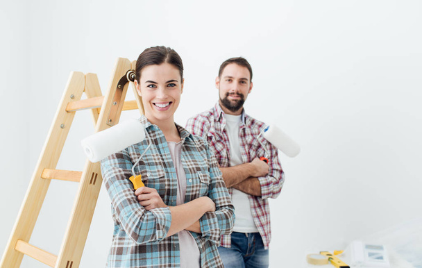couple smiling and holding paint rollers - Foto, imagen