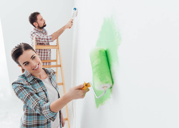 Happy couple painting walls in house - Fotó, kép