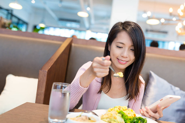 Frau isst zu Mittag und benutzt Handy zusammen - Foto, Bild