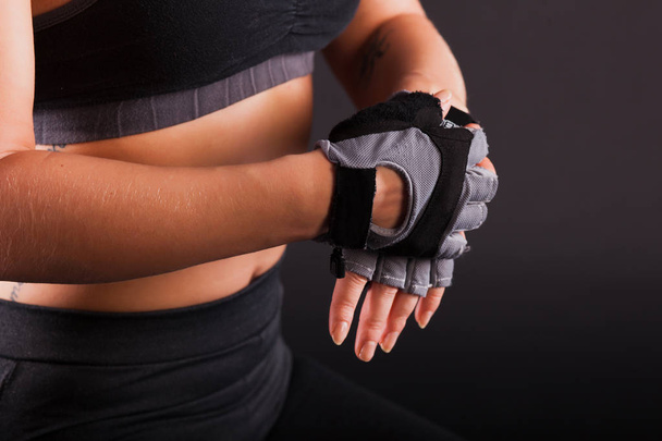 A girl puts on black gloves on her hands for a close-up fitness - Fotó, kép