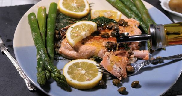 Verter aceite de oliva sobre un delicioso salmón ecológico asado
 - Foto, Imagen
