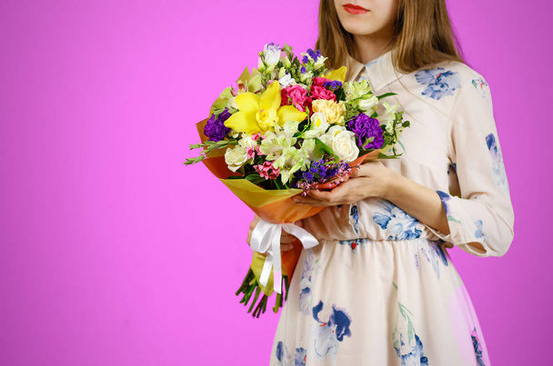 Beautiful girl in dress holding a bouquet of different flowers.  - Фото, изображение