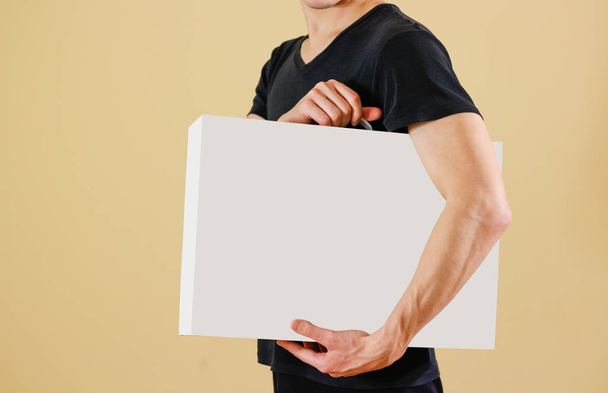 Man in a black shirt holds a white box with a handle. Packing bo - Fotoğraf, Görsel