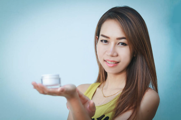 Une belle femme asiatique en utilisant un produit de soins de la peau, hydratant o
 - Photo, image