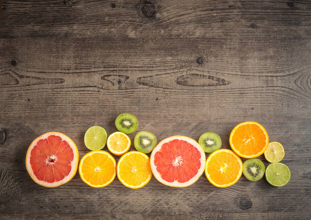 Slices fresh fruits on a brown board with place for a text - Foto, Bild