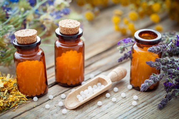 Bottles of homeopathic globules and healing herbs. Homeopathy medicine. - Photo, image