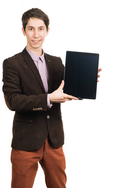Cheerful young man businessman in suit working on digital tablet and smiling while standing isolated - 写真・画像