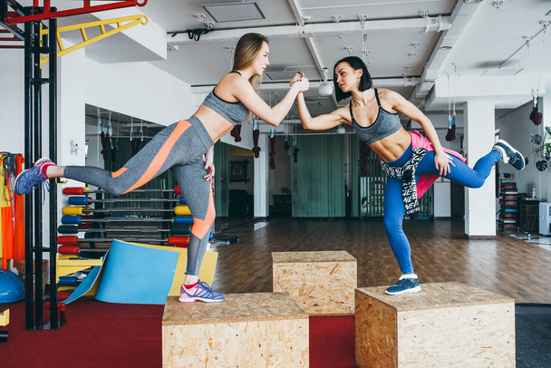 Two beautiful girls together in a fitness room - Zdjęcie, obraz