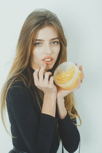 Pretty girl putting gel or balm on sexy lips - Фото, изображение