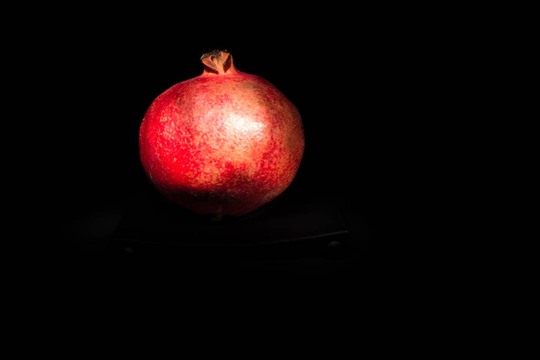 Red pomegranate in front of dark background - Photo, Image