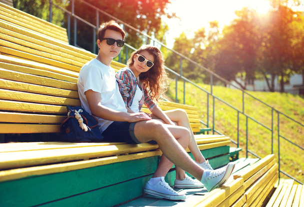 Fashion young couple teenagers resting in the city on bench at s - 写真・画像