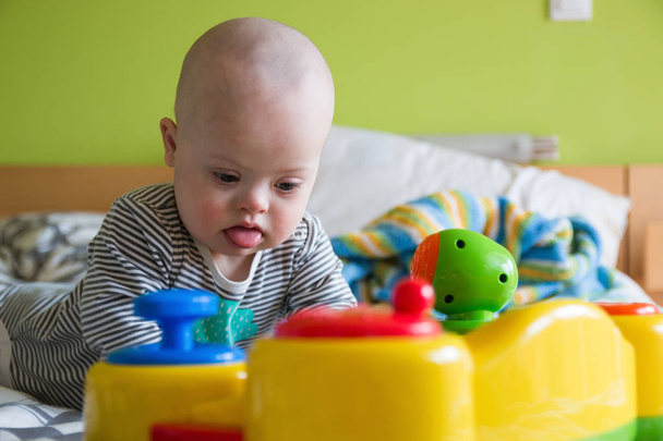 Симпатичный мальчик с синдромом Дауна играет в игрушки
 - Фото, изображение