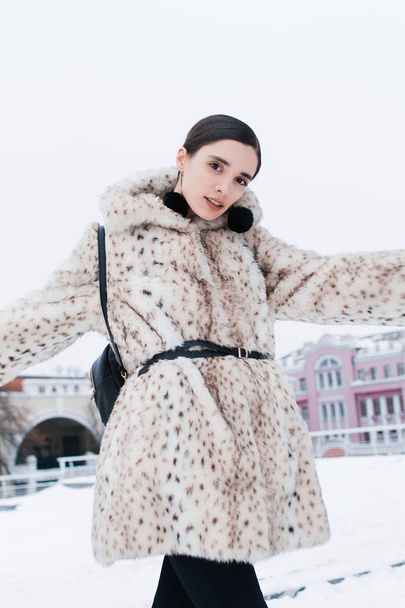 Beautiful business woman in a fur coat on a background of office on the street - Foto, afbeelding