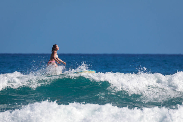 Surfer school. Beautiful young woman in swimsuit goes into ocean - Foto, afbeelding
