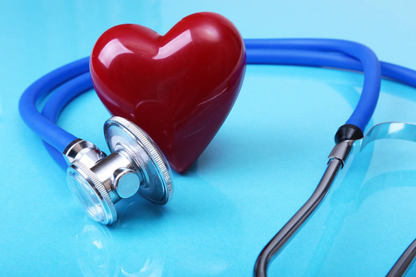Medical stethoscope and red heart isolated on blue mirror background - Foto, Imagen