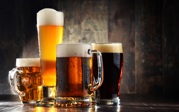 Four glasses of beer on wooden background - Foto, imagen