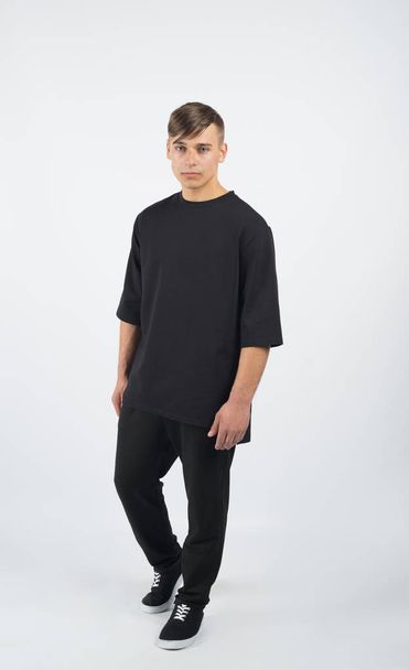 Young muscular man wearing black clothes and sneakers - Fotoğraf, Görsel