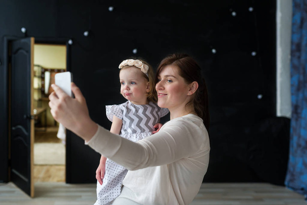Νεαρή όμορφη μητέρα παίρνει αυτοπορτρέτα με την κόρη της - Φωτογραφία, εικόνα