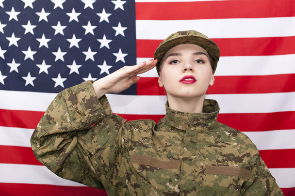Woman soldier in uniform salute in front of  American flag. Portrait - 写真・画像