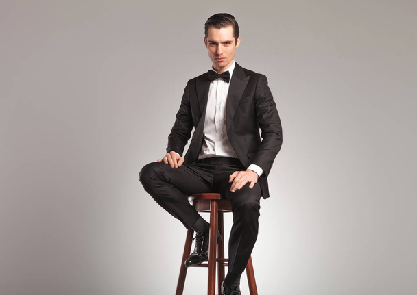 man in tuxedo and bowtie sitting on a stool - Photo, Image