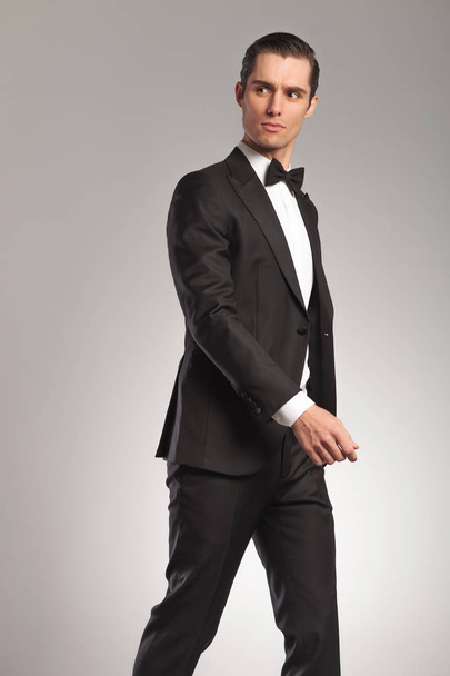 walking young elegant man in tuxedo looking to side - Фото, зображення