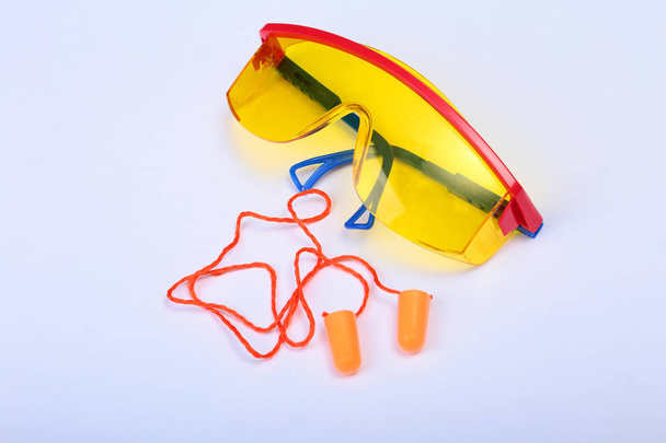 Bouchon d'oreille orange et lunettes de sécurité. Bouchon d'oreille pour réduire le bruit sur fond blanc
 . - Photo, image