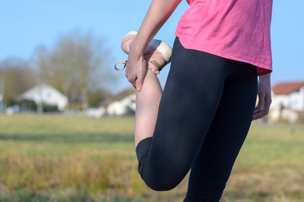Vrouw doet stretching oefening voor joggen - Foto, afbeelding