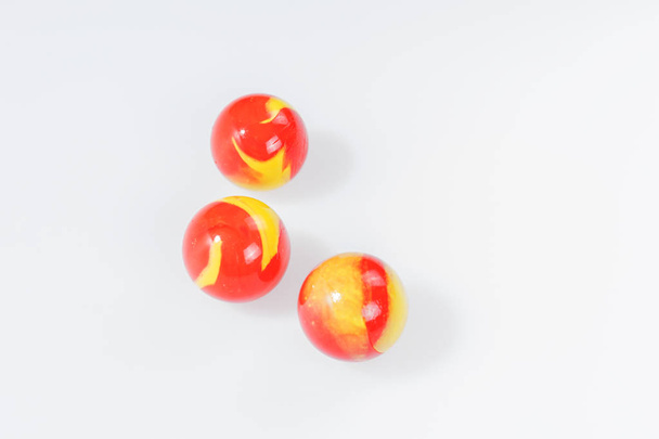 Three red yellow marbles isolated on white - Φωτογραφία, εικόνα