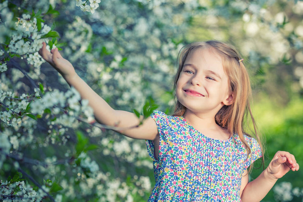 Happy little girl in cherry blossom garden - Foto, imagen