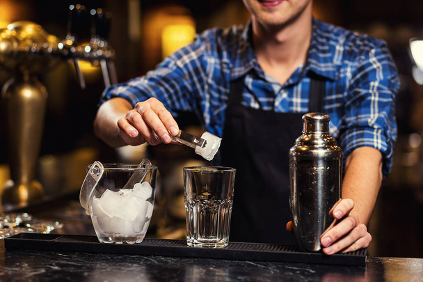Barman en el trabajo, Barman vertiendo espíritu duro en vasos en detalle, Bartender está vertiendo tequila en vidrio, preparando cócteles, concepto sobre servicio y bebidas
 - Foto, imagen