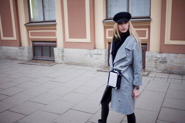 Joven, cadera y atractiva rubia paseando por la ciudad, chica con un sombrero elegante y un abrigo gris
 - Foto, imagen