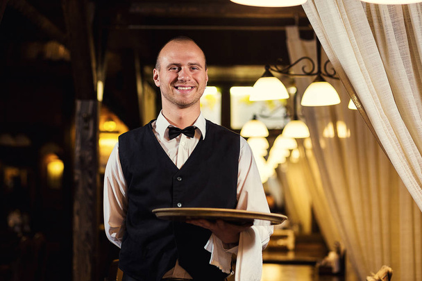 Waiter in uniform waiting an order,waiter order menu,Waiter with a white towel on his hand,Confident waiter,A pub.Bar.Restaurant.Classic.Evening.European restaurant.European bar.American restaurant. - Photo, Image
