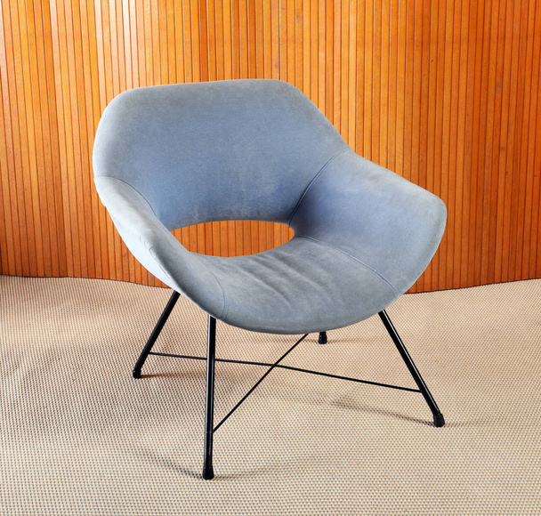 Cadeira de veludo azul retro com pernas pretas no quarto
 - Foto, Imagem