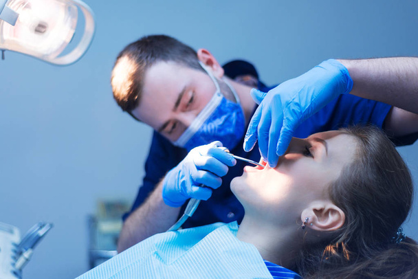 Dentist curing a female patient. getting dental treatment. - 写真・画像