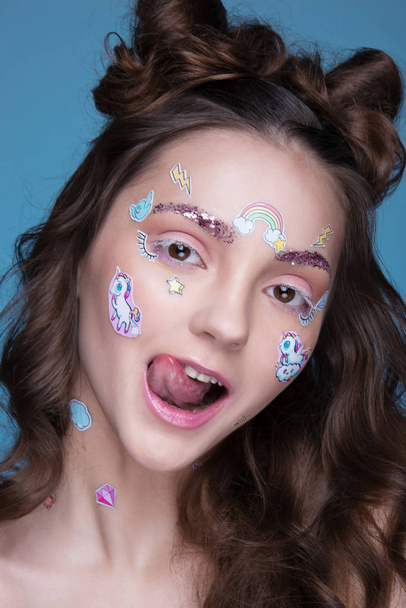 Beautiful fashion girl with funny professional makeup and emoji stickers glued on the face. - Foto, imagen