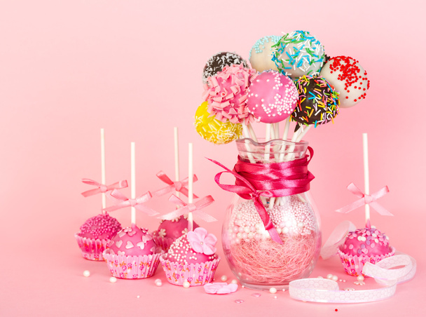 Cake pops met roze suikerglazuur en decoratie op papier vorm en kleur - Foto, afbeelding