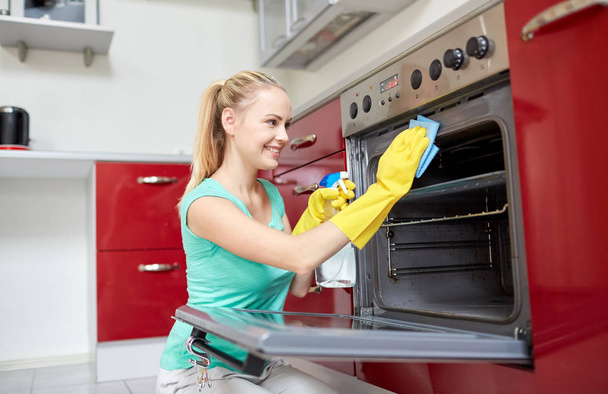 happy woman cleaning cooker at home kitchen - Foto, Bild