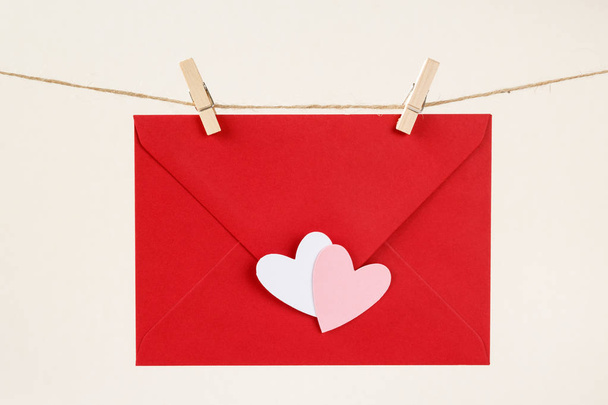 Red envelope with white and pink hearts on a rope with wooden clothespins - Foto, afbeelding